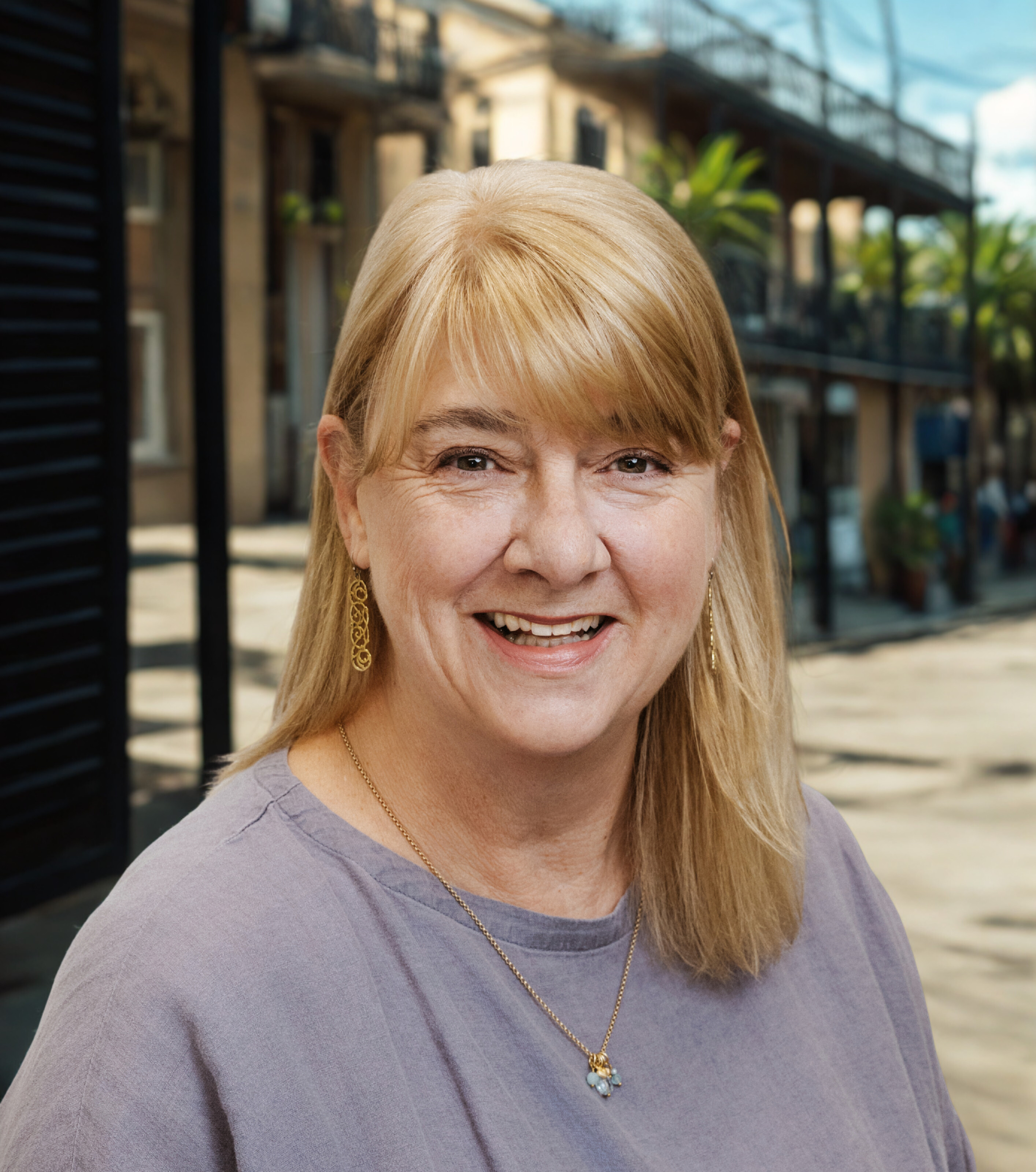 Erin Stopak, REALTOR® with KW New Orleans, professional headshot on a New Orleans balcony street