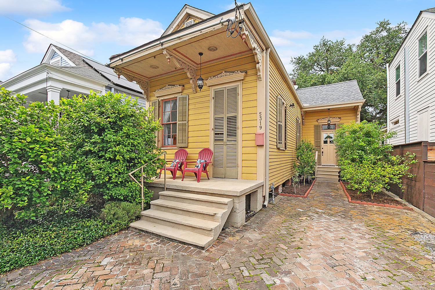 Uptown New Orleans shotgun house porch with red chairs, a home style Erin Stopak specializes in